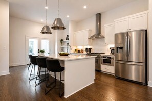 A modern kitchen with a central island, stainless steel appliances, and pendant lighting.