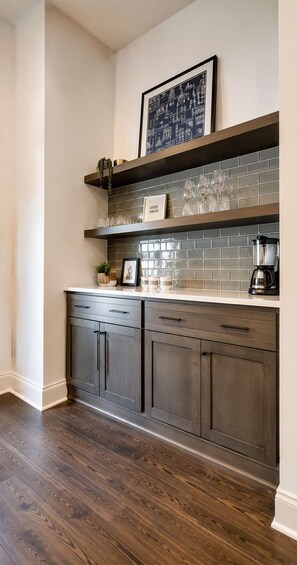 A kitchen with dark wood cabinets, a tiled backsplash, and a coffee maker on the counter.