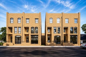 A symmetrical building with a brick facade, multiple windows, and a flat roof. - New Build West End Oasis • Skyline Views (Nashville)
