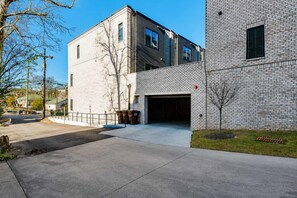 Un bâtiment moderne avec une entrée de garage, une allée pavée et un petit arbre au premier plan.