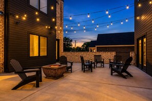 An outdoor patio area with a fire pit, seating, and string lights. - New Build West End Oasis • Skyline Views (Nashville)