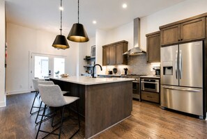 A picture-perfect kitchen with stainless steel appliances and beautiful wooden cabinets. - New Build West End Oasis • Skyline Views (Nashville)