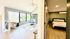 Una habitación de hotel moderna con una cama grande, un escritorio y vistas al exterior a través de amplios ventanales.