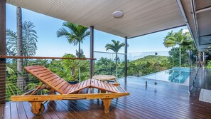 A wooden deck with lounge chairs overlooking a swimming pool and lush greenery. - Stu’s Lookout - Stunning Views (Wongaling Beach)