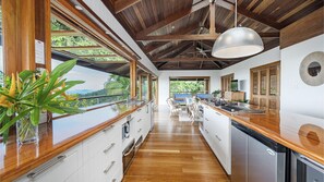 A modern kitchen with wooden countertops, white cabinets, and a view of lush greenery. - Stu’s Lookout - Stunning Views (Wongaling Beach)