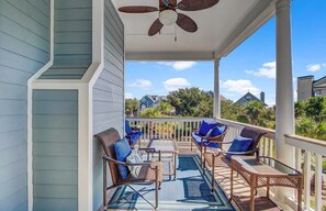 A covered porch with wicker furniture and a ceiling fan.