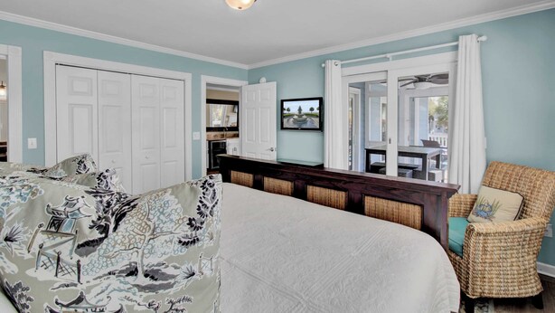 Een slaapkamer met een groot bed, een rieten stoel en uitzicht buiten.