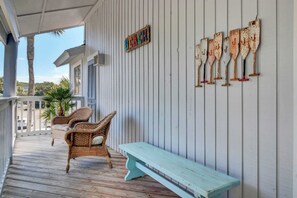 A covered porch with wicker furniture and a light blue bench.