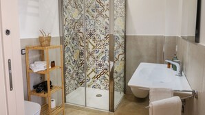 A bathroom with a shower enclosure, a sink, and a toilet.