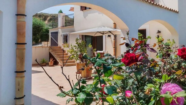 A courtyard with a covered seating area, a staircase, and a view of a hillside.