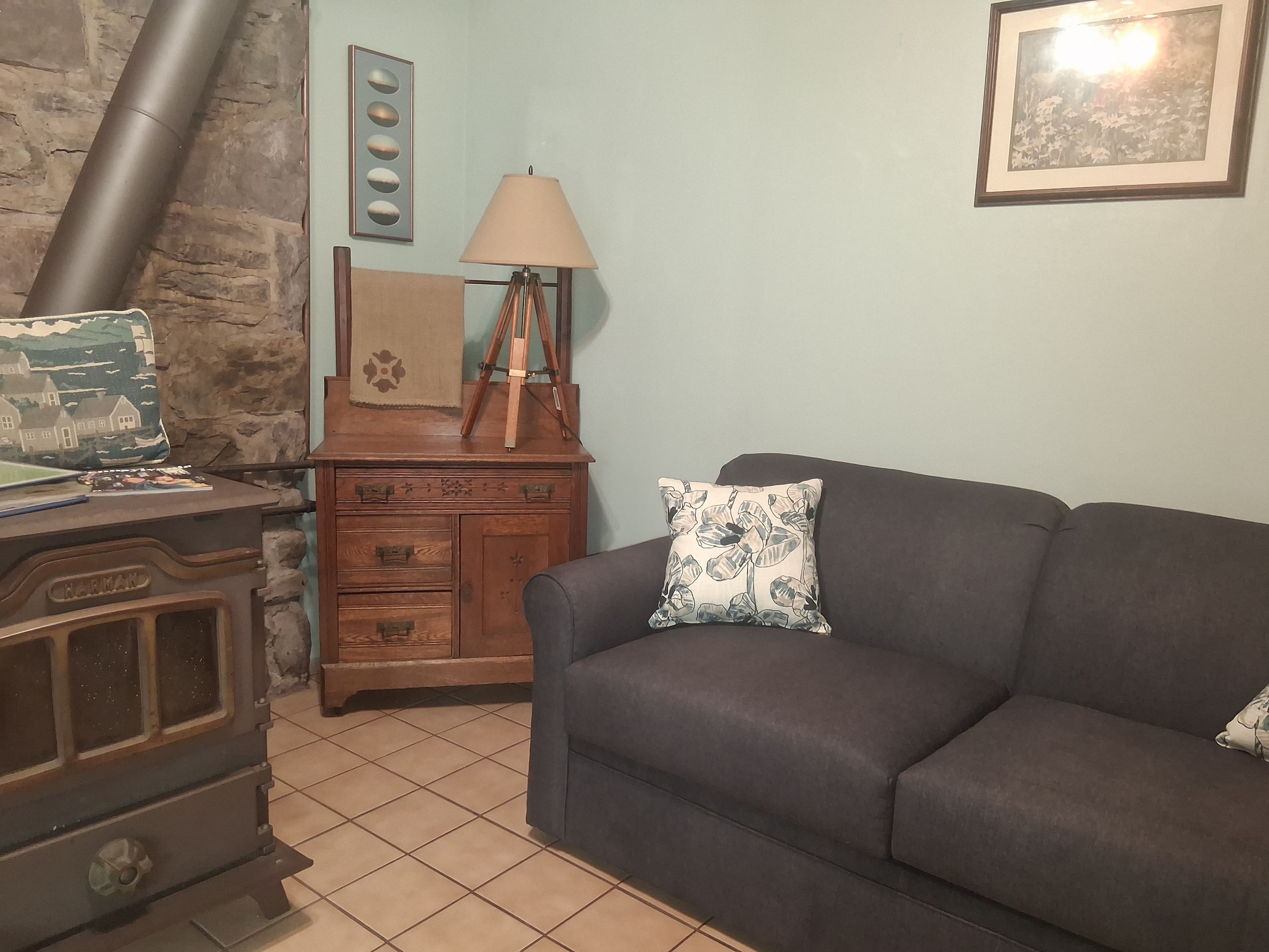 Una sala de estar con un sofá, un aparador de madera, una lámpara y una chimenea.