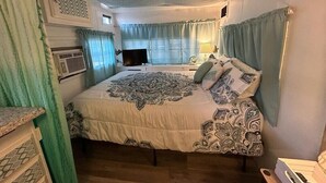 Quarto com uma cama grande, televisão, abajur e janela com cortinas.
