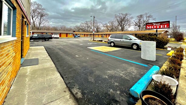 A motel with a parking lot, a sign reading "Your Motel," and a building with a brick facade. - Your Motel (Ypsilanti)