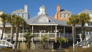 A coastal house with a covered porch, white railings, and palm trees. - 311 Summerhouse by Avantstay Beach Views Access to Community Pool (Isle of Palms)