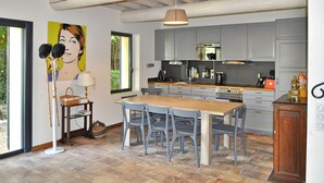 Uma cozinha moderna com armários cinzas, uma mesa de jantar de madeira e cadeiras azuis.