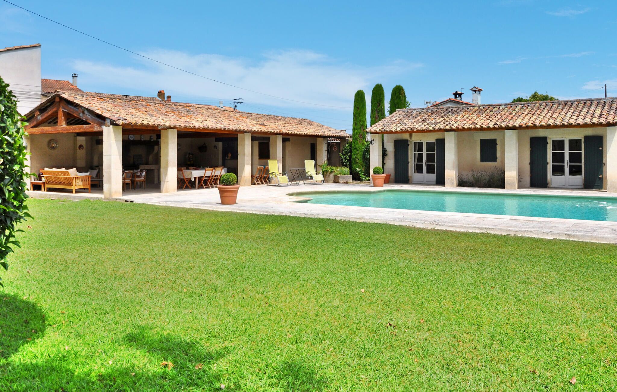 A two-story house with a swimming pool, outdoor seating, and a well-maintained lawn.