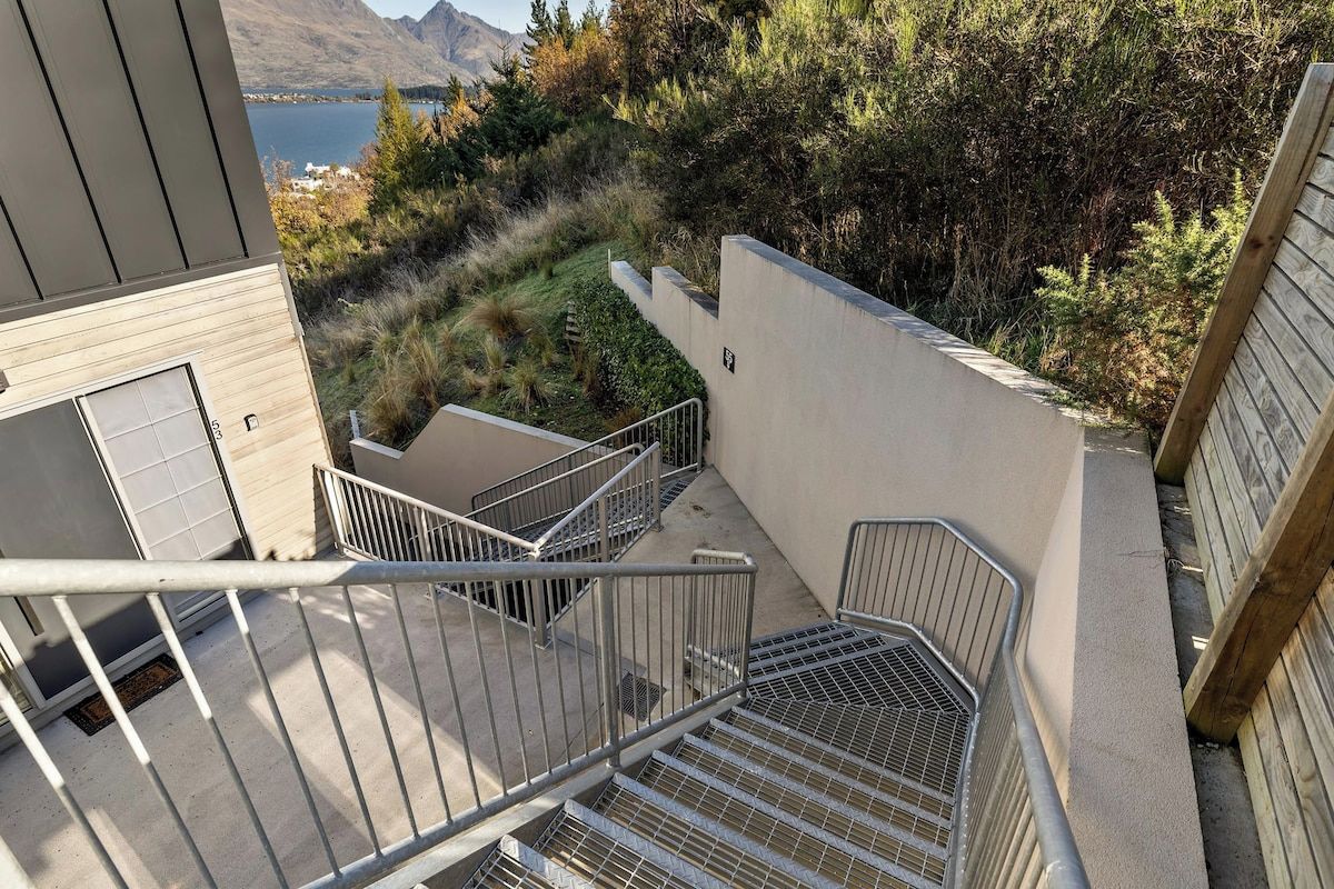 A staircase leading to a balcony with a view of a lake and mountains.