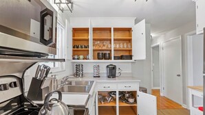 Eine moderne Küche mit weißen Schränken, einem eingebauten Ofen und einer Kaffeemaschine.