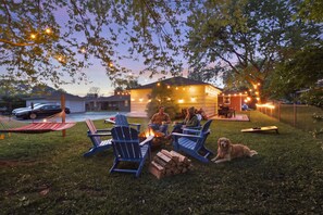 A backyard with a fire pit, outdoor seating, and a dog. - Comfy King Bed | Family Friendly | Games | Dogs OK (Columbus)