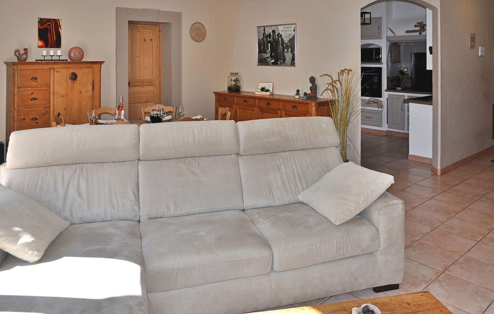 Una sala de estar con un sofá color beige, armarios de madera y una cocina al fondo.