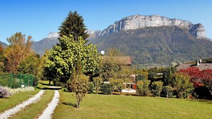 A rural landscape with a mountain in the background, a pathway, and a house with satellite dishes.