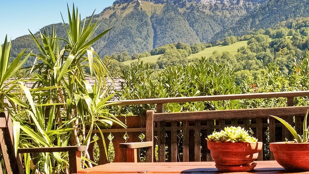 A wooden deck with potted plants and a mountain view.