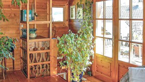 A wooden cabin interior with a large window, wooden shelves, and a potted plant.