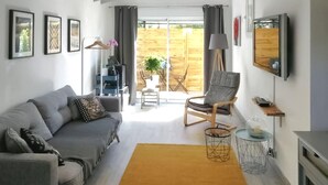 A modern living room with a grey sofa, a wooden chair, a yellow rug, and a glass coffee table.