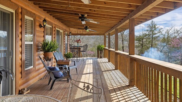 A wooden deck with a covered area, outdoor furniture, and a view of trees and mountains. - Eagles Roost.  Wifi & Dog Friendly.  Covered porch & upper Deck w/ Sunset Views (Eagle Rock)