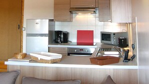 A compact kitchen with a refrigerator, microwave, coffee maker, and a small sink.