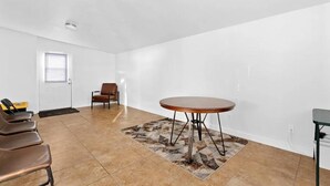 Una habitación amplia con una mesa redonda, algunas sillas y una puerta.