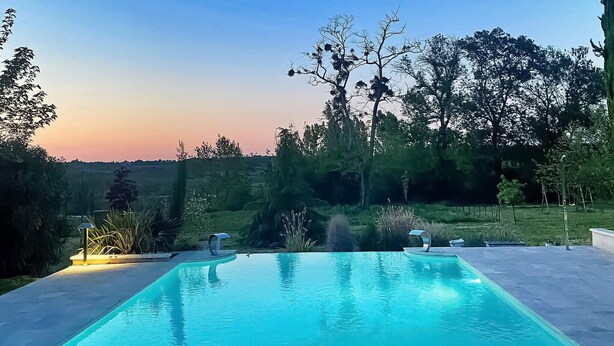 A rectangular swimming pool with a clear blue water surface, surrounded by a concrete deck.