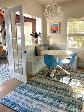 A dining area with a round table, blue chairs, and a patterned rug. - Northwood Haven (West Palm Beach)