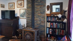 A cozy living room with a stone wall, a fireplace, a bookshelf, and a television.