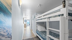 Een kamer met stapelbedden, uitzicht op zee en een rond raam.