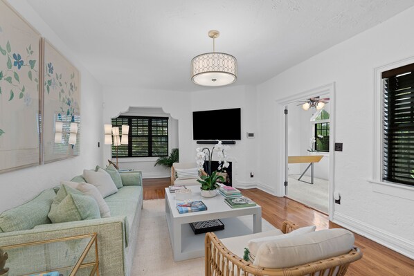 A modern living room with a sofa, a coffee table, a TV, and a ceiling fan.