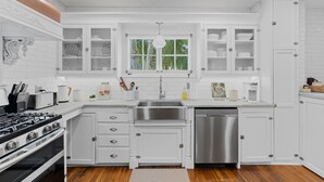 A modern kitchen with white cabinetry, a stainless steel sink, and a built-in dishwasher. - Casa Michaeline Vacation Home (West Palm Beach)