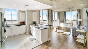 Una cocina moderna con armarios blancos, una isla central y un comedor con sofá y mesa.