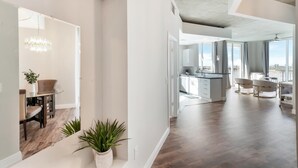 Un espacio habitable amplio con una cocina moderna, un comedor con mesa de vidrio y vistas a la ciudad.
