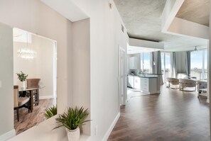 Un'ampia zona giorno con cucina moderna, un'area pranzo con tavolo in vetro e vista sulla città.