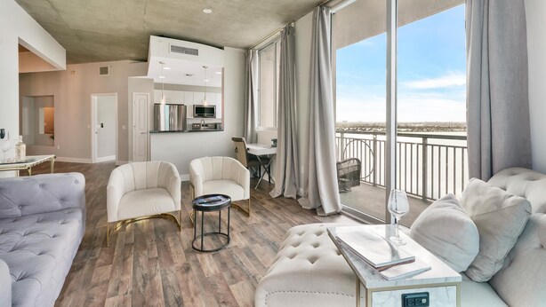 Amplia sala de estar con balcón, muebles modernos y zona de cocina.