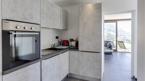 A modern kitchen with a built-in oven, a sink, and a countertop. There is a view of a balcony with a chair and a table. - Awesome apartment in Talloires-Montmin (Talloires-Montmin)