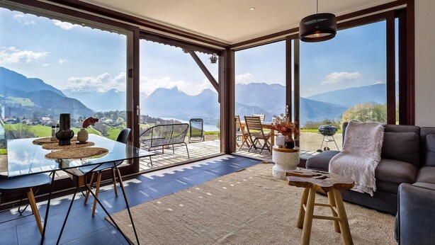 A spacious room with large windows offering a mountain view, a glass dining table, and a comfortable seating area. - Awesome apartment in Talloires-Montmin (Talloires-Montmin)