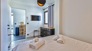 A modern hotel room with a bed, a TV mounted on the wall, a dresser, and a window with curtains. - Awesome apartment in Talloires-Montmin (Talloires-Montmin)
