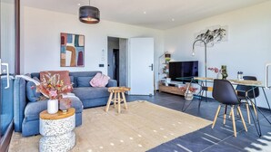 A modern living room with a sofa, coffee table, and a dining area with a TV and table. - Awesome apartment in Talloires-Montmin (Talloires-Montmin)