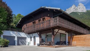 A wooden chalet with a balcony, a covered patio area, and a mountain backdrop. - Awesome apartment in Talloires-Montmin (Talloires-Montmin)