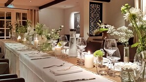 A long dining table set with candles, glassware, and floral centerpieces.