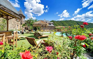 A stone house with a thatched-roof structure, a swimming pool, and lush greenery. - Stunning home in La Fouillade (La Fouillade)