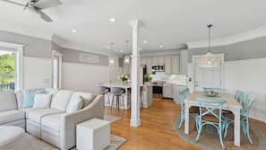 A modern kitchen with white cabinetry, a central island, and a dining area with blue chairs.
