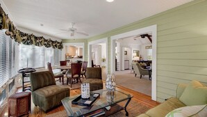 A spacious living room with a dining area, a kitchen in the background, and a ceiling fan. - 12 Dunecrest Lane by Avantstay 2 Mins to Beach w/ Pool & BBQ (Isle of Palms)